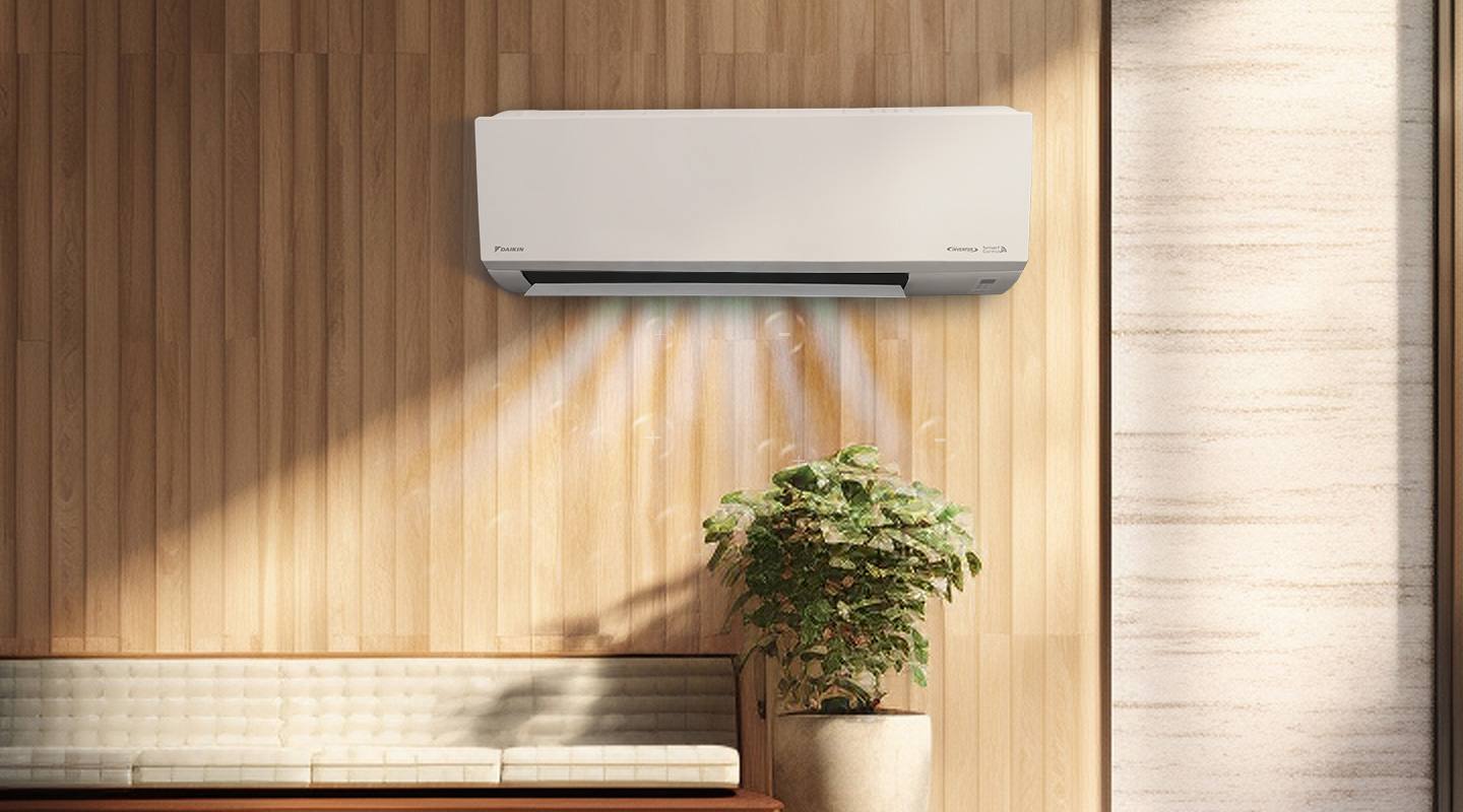 Unit aircond Daikin pada dinding panel kayu bersebelahan pokok hiasan